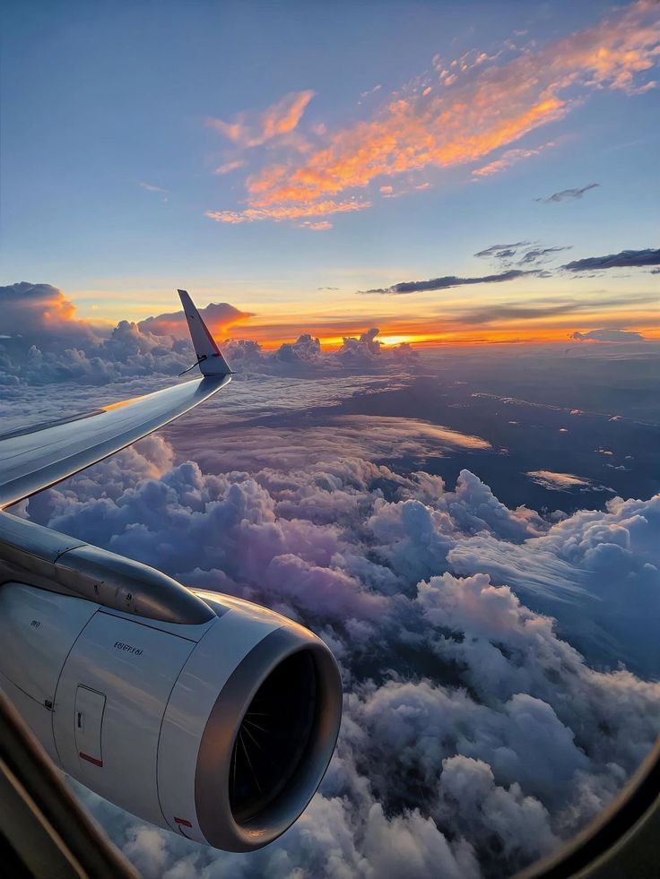 View above the clouds from an airplane window at sunset